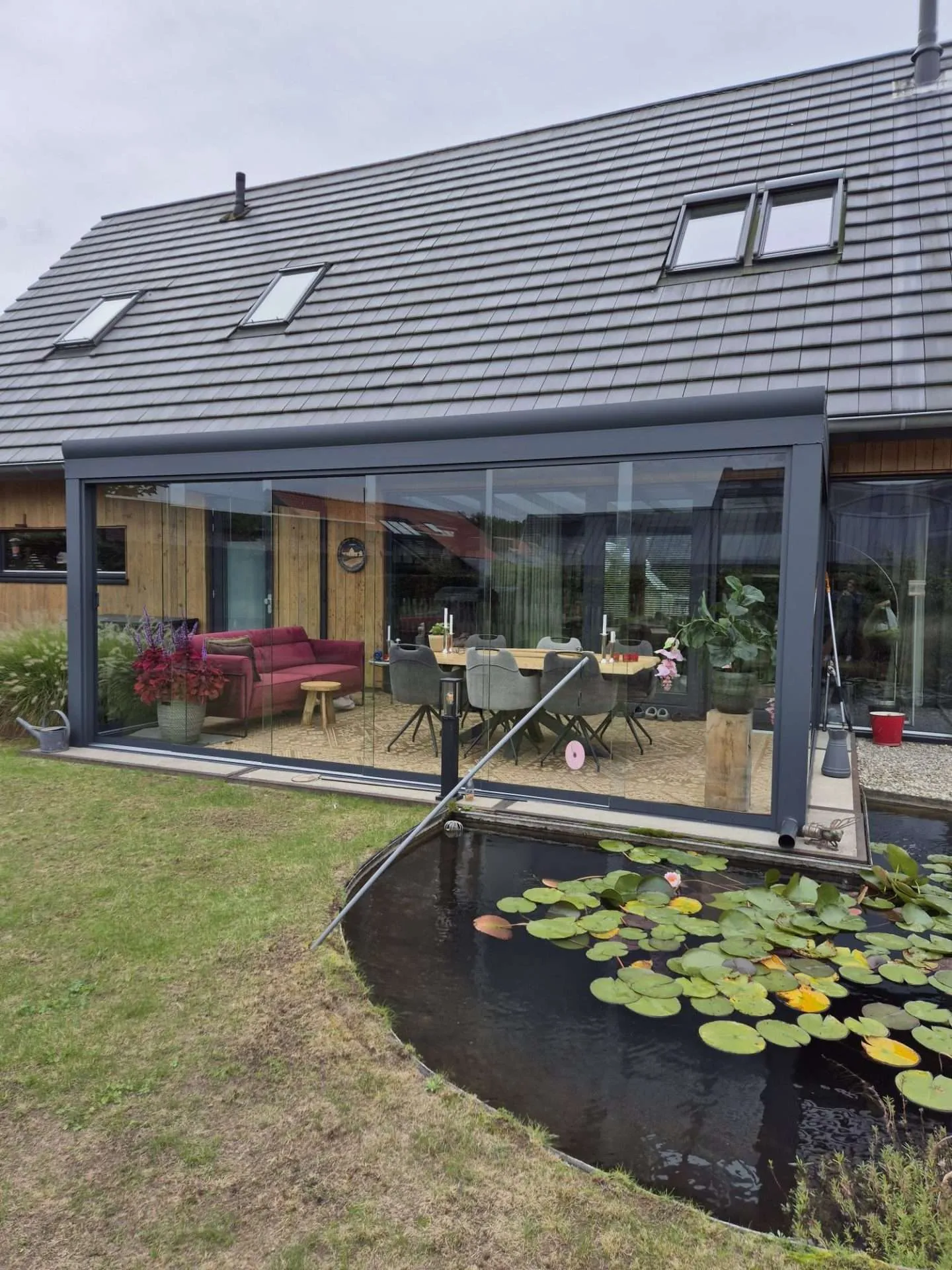 Veranda mit Glas-Schiebewänden am Gartenteich