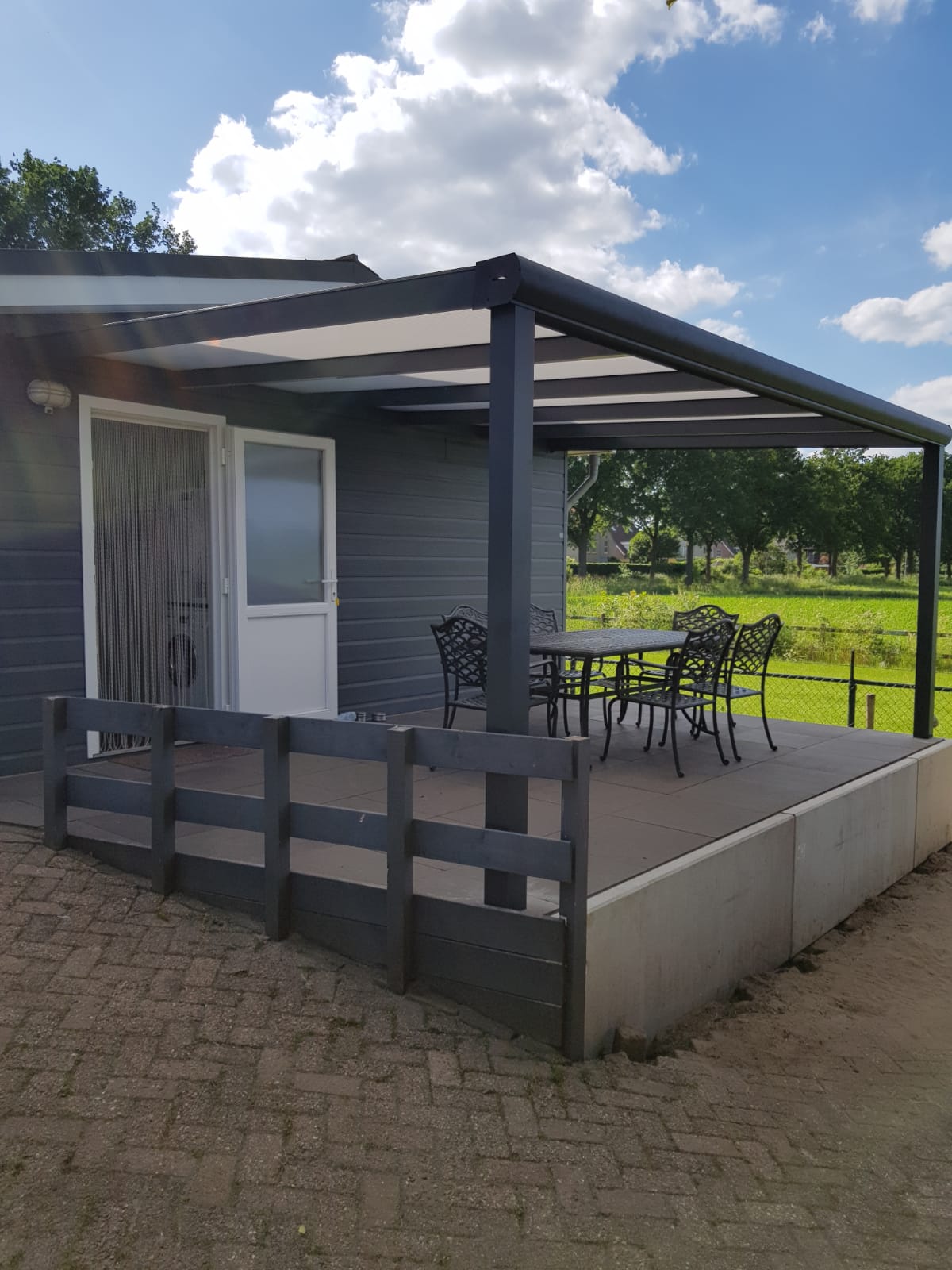 Aluminium-Terrassenüberdachung mit Sitzplatz im Grünen